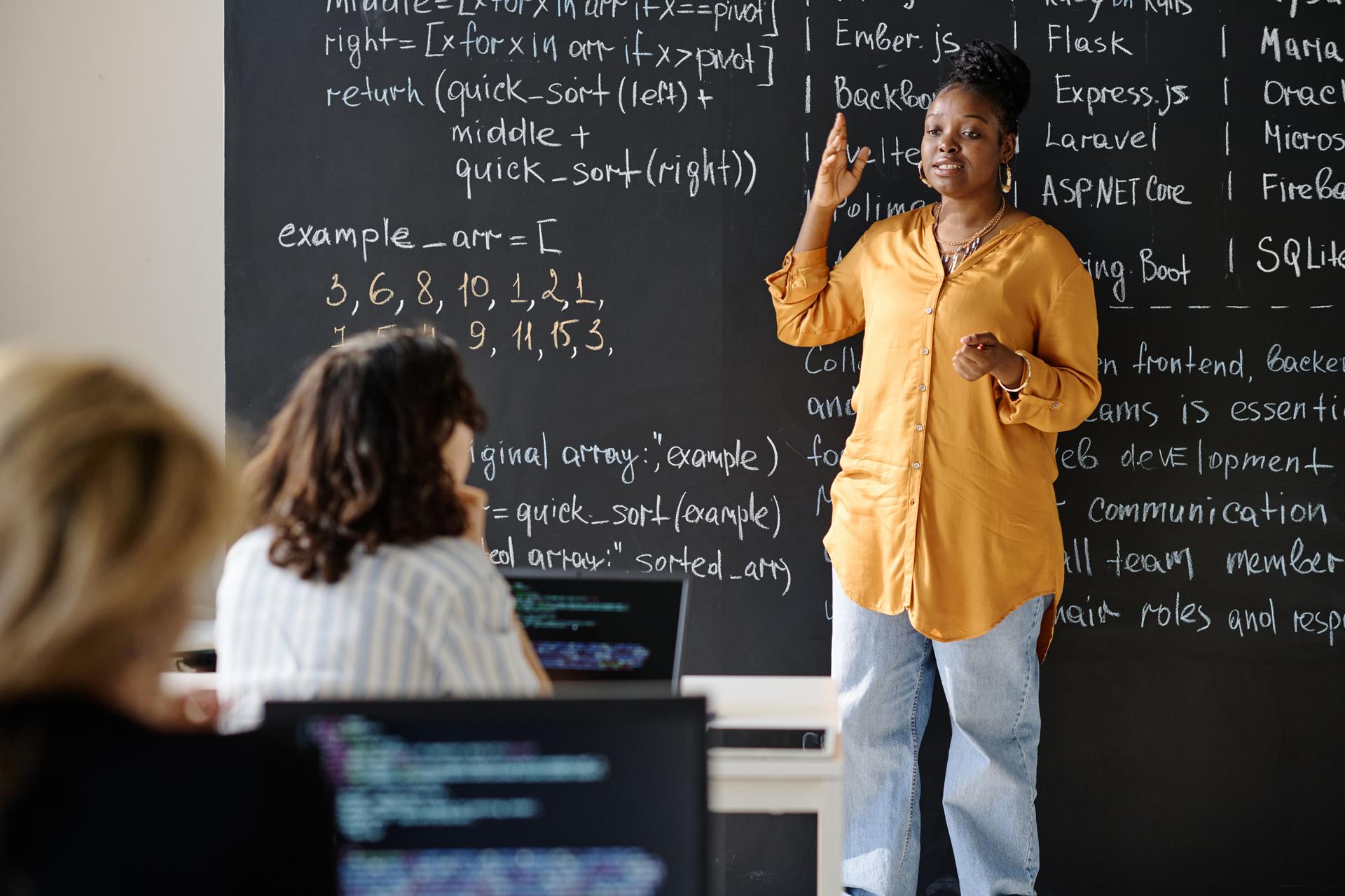 Teacher teaching IT lesson to students at class